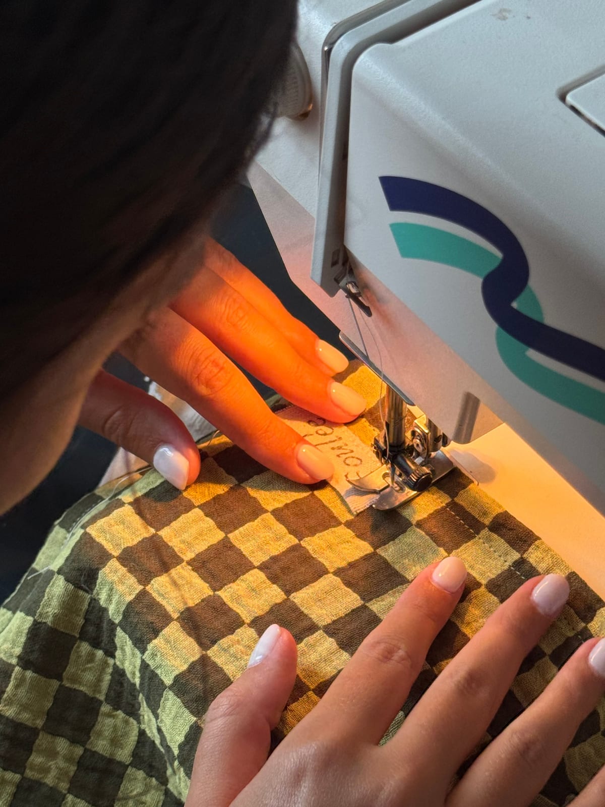 À l'atelier Foulée : les mains sur la machine, l'étiquette cousue sur un foulard